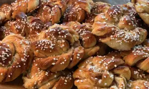 En hög med nybakade kanelbullar, perfekta att baka med flytande margarin. Strösslade med pärlsocker.