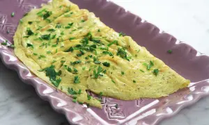 En perfekt vikt omelett med gräslök, redo att serveras. Ett enkelt omelett recept för en snabb och god måltid.