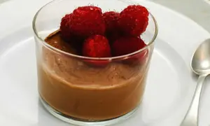 En krämig choklad pannacotta toppad med färska hallon i ett glas. En perfekt dessert för alla chokladälskare.