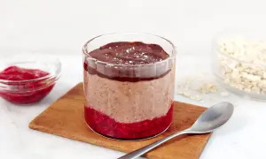 Choklad overnight oats med hallon och en sked redo att avnjutas.