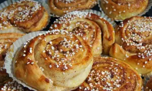 Nybakade kanelbullar med pärlsocker, redo att avnjutas. Doften av kanel och socker sprider sig från dessa gyllene tina frysta bullar i ugn.