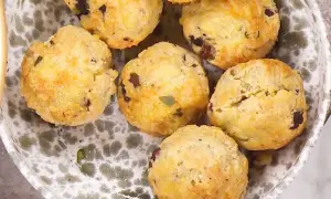 En skål med matiga scones, gyllene och med mörka bitar av oliver eller soltorkade tomater. Perfekta för en rejäl fika.