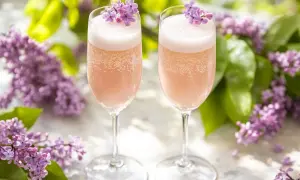 Två glas rosa bubbel med syrenblommor, perfekt för ett syrensirap recept.