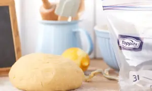 En deg ligger på ett mjölat bord, redo att frysa. Bredvid finns en citron och en fryspåse.