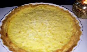 En gyllene ananaspaj glutenfri med en krämig fyllning. En ljuslykta glimmar i bakgrunden.