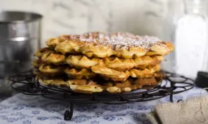 En hög med nybakade, pudrade våfflor som väntar på att serveras. Perfekt för en mysig fika.