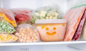 Frysta grönsaker och bär i frysen. En burk med glad smiley visar hur länge deg håller i kylen.