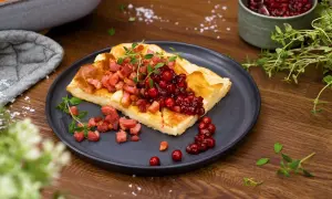 En bit ugnspannkaka med knaperstekt bacon och rårörda lingon, garnerad med färska örter. En klassisk svensk rätt.