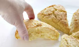 En hand plockar en gyllene scones. Bra att veta om man kan frysa scones för senare njutning.