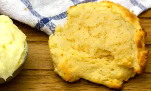 En fluffig scone bredvid en skål med mjukt, flytande margarin, redo att avnjutas.