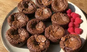 Kladdkakemuffins recept: Mörka, saftiga kladdkakemuffins på en tallrik med färska hallon. Perfekt för fikat!