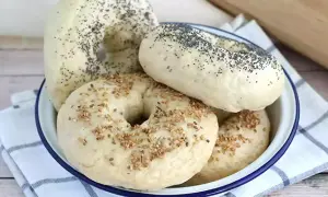 Färska bagels med vallmofrön och sesamfrön i en skål, redo för ditt bagels recept.