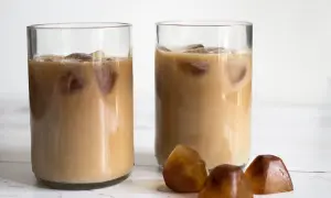 Två glas med iskaffe, perfekt för ett enkelt iskaffe recept. Tre kaffekuber ligger framför.