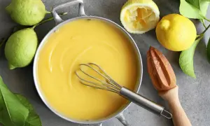 Kastrull med krämig lemon curd, färska citroner och en träpress. Perfekt för bakning!