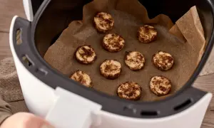Små, runda kakor med kanel ligger på bakplåtspapper i en airfryer. Perfekt för att frysa in kakor för senare njutning.