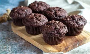 Fem amerikanska muffins med chokladbitar på en träbricka.