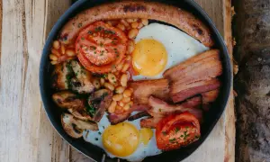 En rejäl engelsk frukost i en stekpanna: korv, ägg, bacon, bönor, tomater och champinjoner.