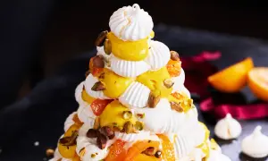 Julig pavlova i juletid, dekorerad med krämig vaniljkräm, aprikoser och pistagenötter.