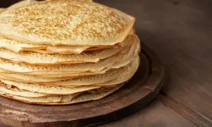 En hög med gyllene pannkakor på en träbricka, redo att frysa in pannkakor för framtida frukostar.