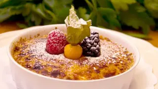En krämig crema catalana med karamelliserad yta, toppad med hallon, björnbär och physalis.