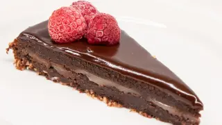En bit kladdkaka med After Eight-smak, toppad med tre hallon på en vit tallrik.