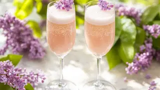 Två glas rosa bubbel med syrenblommor, perfekt för ett syrensirap recept.