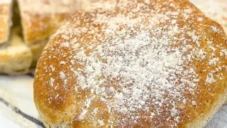 Nybakade skons, pudrade med mjöl, ligger på en randig kökshandduk.