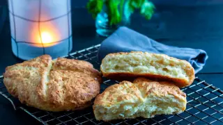 Njut av nybakade, klassiska scones på ett galler. En ljuslykta och en blå duk skapar en mysig stämning.