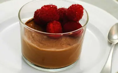 En krämig choklad pannacotta toppad med färska hallon i ett glas. En perfekt dessert för alla chokladälskare.