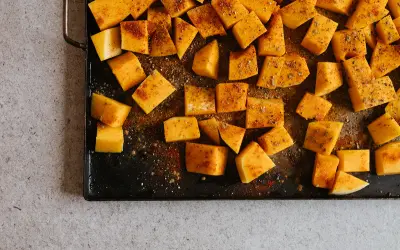 Tärnad pumpa kryddad och redo för ugnen. Ett enkelt steg i ett gott pumpapure recept.
