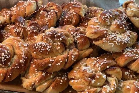 En hög med nybakade kanelbullar, perfekta att baka med flytande margarin. Strösslade med pärlsocker.