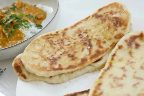 Nybakade, gyllene naanbröd med strössel av flingsalt, perfekta till en krämig curry. Ett enkelt naan recept för hemmabruk.