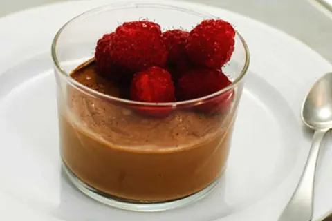 En krämig choklad pannacotta toppad med färska hallon i ett glas. En perfekt dessert för alla chokladälskare.