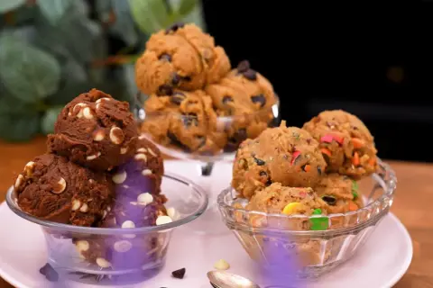 Tre skålar med olika sorters cookie dough recept: choklad med vita chokladknappar, klassisk med chokladknappar och färgglad med godisbitar.