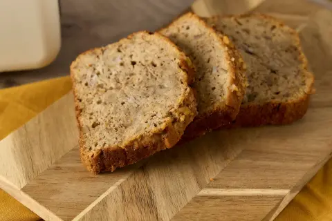 Skivor av bananbröd på en träskärbräda. Frågan "hur länge kan man frysa bröd" dyker upp när man ser hur färskt det ser ut.