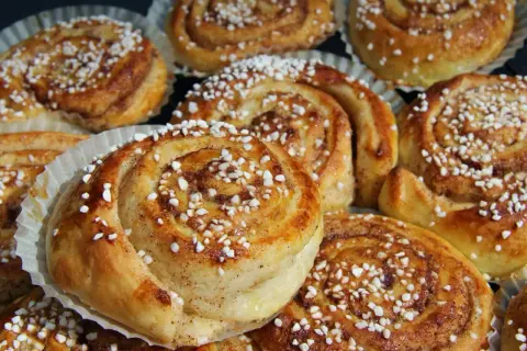 Nybakade kanelbullar med pärlsocker, redo att avnjutas. Doften av kanel och socker sprider sig från dessa gyllene tina frysta bullar i ugn.