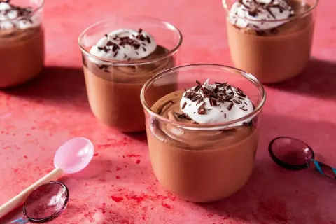 Chokladmousse recept: Krämig chokladmousse i glas, toppad med vispad grädde och chokladspån. Perfekt för en lyxig dessert.