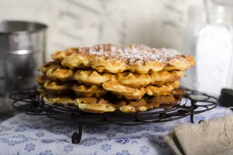 En hög med nybakade, pudrade våfflor som väntar på att serveras. Perfekt för en mysig fika.