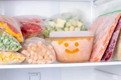 Frysta grönsaker och bär i frysen. En burk med glad smiley visar hur länge deg håller i kylen.
