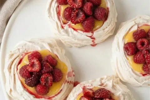 Små marängbottnar fyllda med krämig lemoncurd och toppade med färska hallon och jordgubbar. En härlig pavlova!