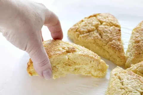 En hand plockar en gyllene scones. Bra att veta om man kan frysa scones för senare njutning.