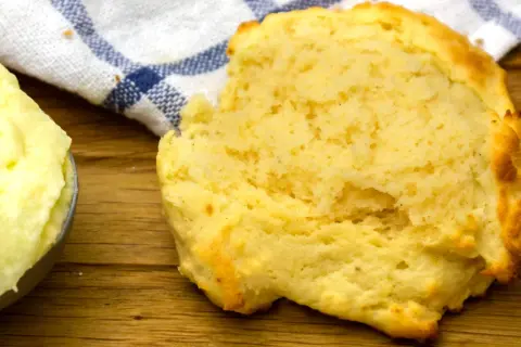 En fluffig scone bredvid en skål med mjukt, flytande margarin, redo att avnjutas.