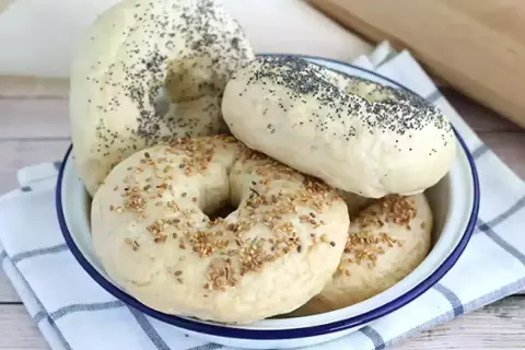 Färska bagels med vallmofrön och sesamfrön i en skål, redo för ditt bagels recept.