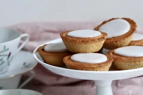 En hög med hembakade mazariner med vit glasyr, redo att avnjutas. Perfekt för ett fika-tillfälle, kanske med ett gott mazariner recept.