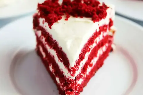 En saftig bit red velvet cake med krämig frosting och smulor på toppen.