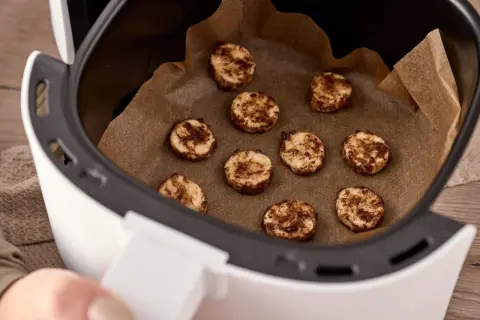 Små, runda kakor med kanel ligger på bakplåtspapper i en airfryer. Perfekt för att frysa in kakor för senare njutning.