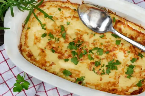 En gyllene omelett i ugn, toppad med färsk persilja och en sked redo att servera. Perfekt för en mysig frukost eller brunch.