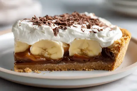 En bit krämig banoffee paj med banan, kolasås, vispgrädde och chokladströssel.