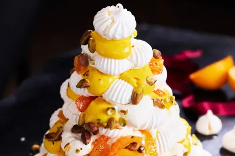 Julig pavlova i juletid, dekorerad med krämig vaniljkräm, aprikoser och pistagenötter.