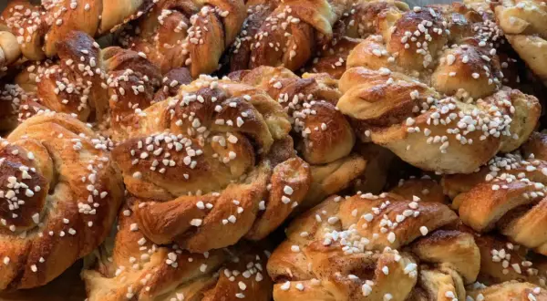 En hög med nybakade kanelbullar, perfekta att baka med flytande margarin. Strösslade med pärlsocker.